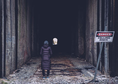 Rear view of woman standing in tunnel