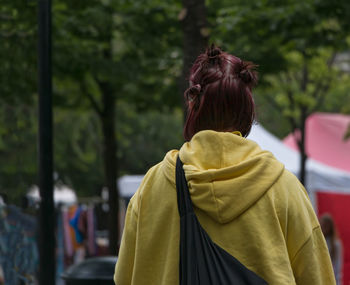 Rear view of woman wearing yellow hooded shirt