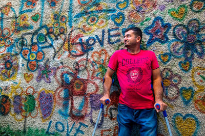 Portrait of man standing against graffiti wall