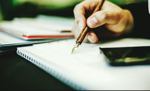 Cropped hand of person writing in book