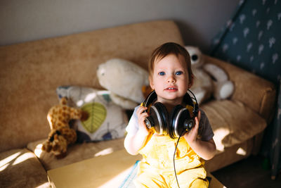 Funny little child having fun with headphones at home, portrait.