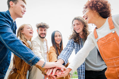 Cheerful friends stacking hands outdoors