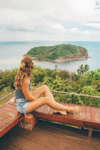 Side view of woman sitting on wooden seat