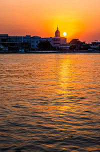 View of sea against buildings during sunset