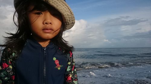 Close-up of boy standing at beach against sky