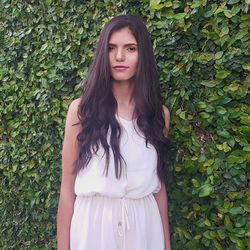 Portrait of young woman standing against leaves