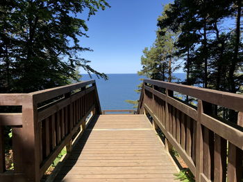 View of wooden footbridge against clear sky