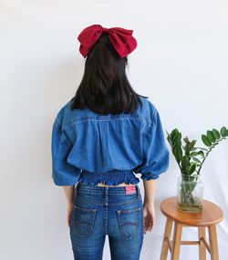 Fashion shot of woman in jeans top and big red hair bow isolated over white backgrounds 