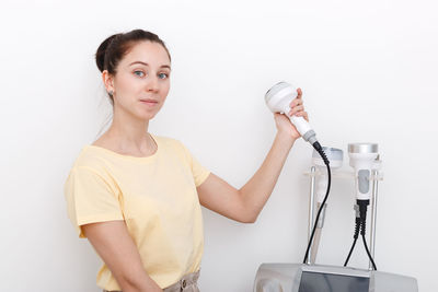 Portrait of young woman standing against white background