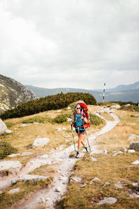 Rear view of man walking on mountain against sky