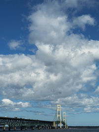 Bridge over sea against cloudy sky