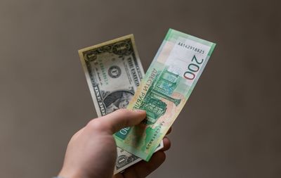 Close-up of man holding money against brown background