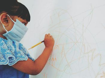 Girl wearing mask drawing on wall