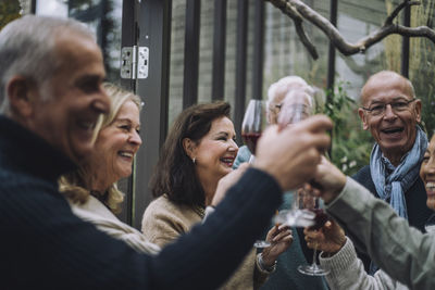 Cheerful retired male and female friends toasting drinks at dinner party