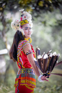 Portrait of young woman standing against trees