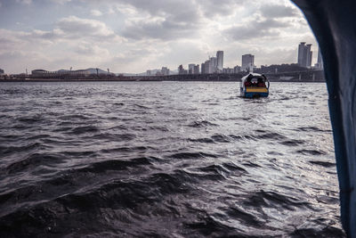 Boat sailing on sea against buildings in city