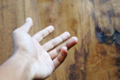 Cropped hand against wooden wall