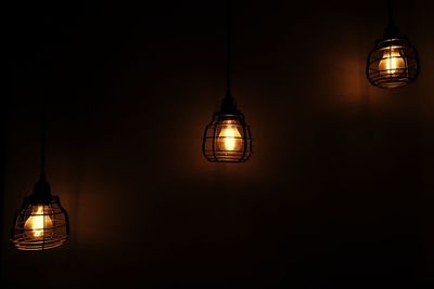 Illuminated light bulbs hanging in darkroom