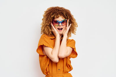 Portrait of young woman wearing sunglasses while standing against white background