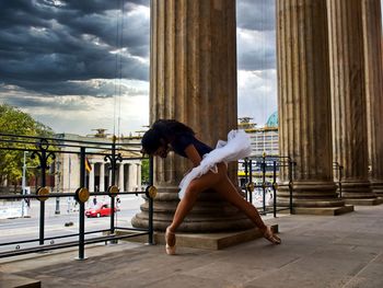 Side view of woman sitting against cloudy sky