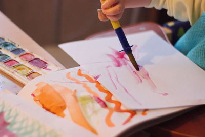 Midsection of baby painting on paper at home