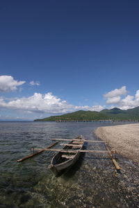 Boat moored on beach against sky