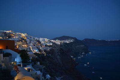 Town by sea against clear sky at dusk