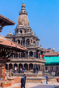 People in front of historic building against blue sky