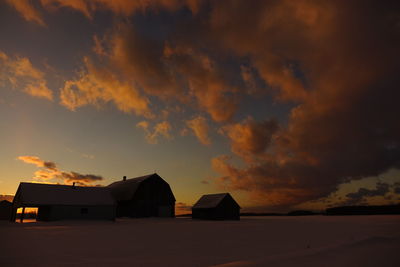 Silhouette houses against sky at sunset