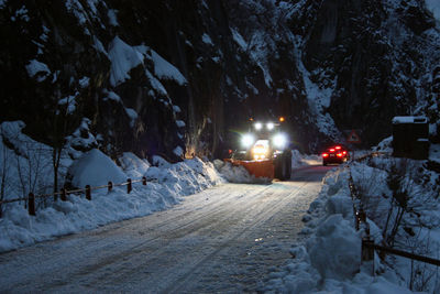 Snow covered road amidst trees during winter