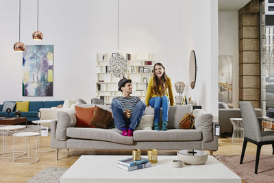 Couple in modern furniture store sitting on couch, laughing