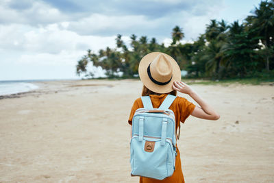 Rear view of man wearing hat standing on beach