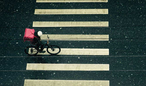 High angle view of man riding bicycle on road during rain