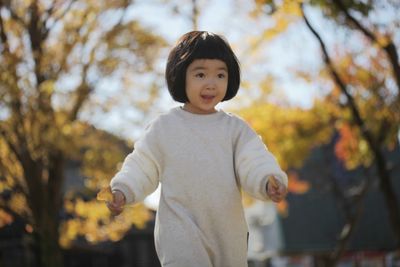 Boy standing against trees during autumn