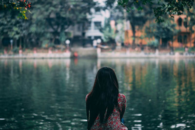 Rear view of woman sitting at lakeshore