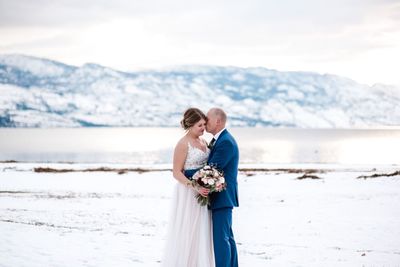 Rear view of couple standing on shore against sea