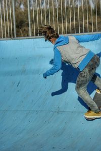 Full length rear view of woman skateboarding on sports ramp