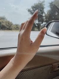 Cropped image of hand on car window
