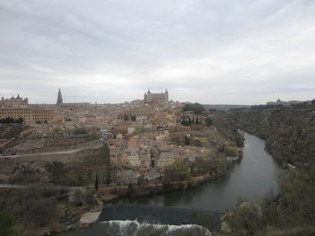 River by city against cloudy sky