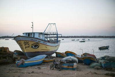 Boats moored at harbor against clear sky