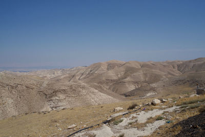 Scenic view of arid landscape against clear blue sky