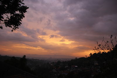 Cityscape against cloudy sky at sunset