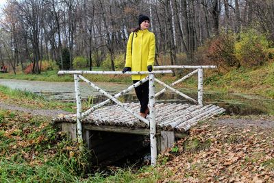 Full length of woman standing on footbridge over stream