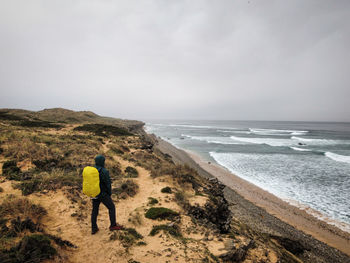 Rear view of woman walking on beach against sky