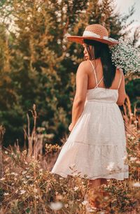 Rear view of woman standing by tree on field