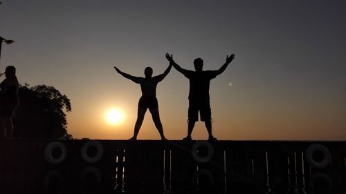 Silhouette men against sky during sunset