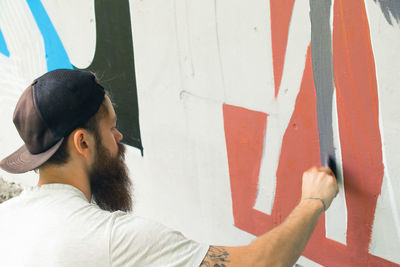 Close-up of street artist painting graffiti on wall