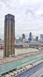 Cityscape by river against sky