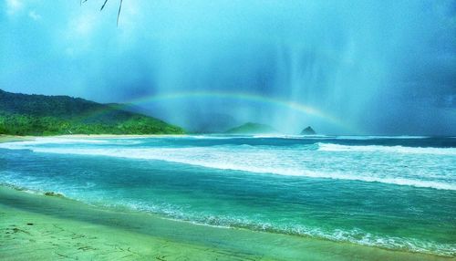 Scenic view of sea against rainbow in sky