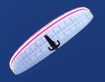 Directly below shot of person paragliding against clear blue sky